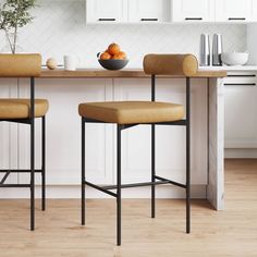 two brown stools sitting in front of a kitchen counter with fruit on top of it