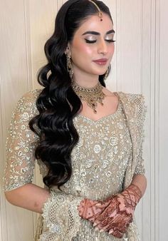 a woman with long black hair wearing a white dress and gold jewelry on her hands