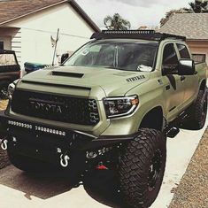 a green toyota truck parked in front of a house