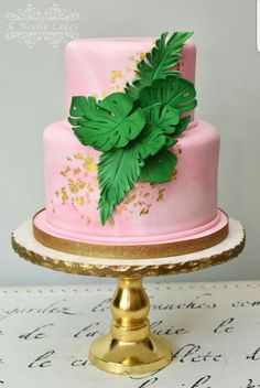 a pink and gold cake with green leaves on top