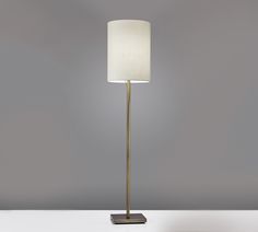 a floor lamp with a white shade on it's base and a black square base