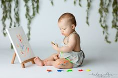 a baby sitting on the floor playing with an easel