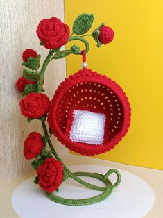 a crocheted vase with red flowers on it