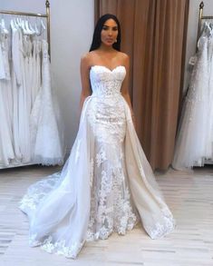 a woman is standing in front of some wedding dresses