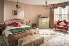 a bedroom with a bed, dresser and chair next to a chandelier hanging from the ceiling