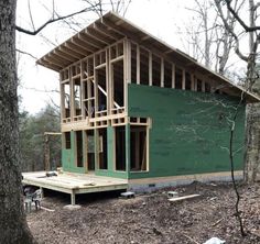 a house being built in the woods with wood framing on it's walls and roof