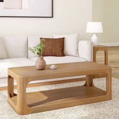 a living room with a white couch and wooden coffee table in front of a painting on the wall