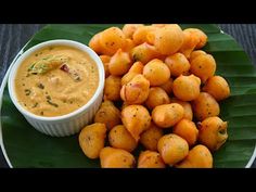 a plate full of fried food with dipping sauce on the side and green leafy leaves