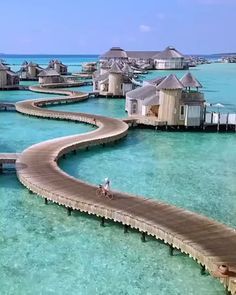 a person riding a bike on a wooden walkway in the middle of clear blue water