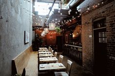 an empty restaurant with tables and chairs in front of the bar, lights hanging from the ceiling