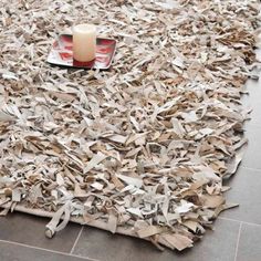 a pile of newspaper sitting on top of a floor next to a candle