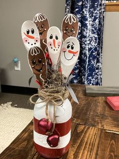 a mason jar filled with wooden spoons decorated like snowmen and santa clausers