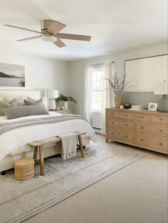 a bedroom with a large bed, dresser and ceiling fan in the middle of it