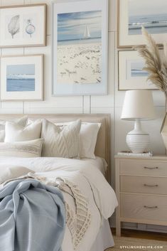 a bedroom with white walls and pictures on the wall above the bed, along with two lamps