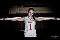 a female basketball player with her arms stretched out in the air and wearing a white jersey