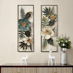 two metal wall art pieces with flowers and leaves hanging on the wall next to each other