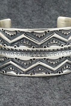 This stunning sterling silver bracelet was made by Navajo silversmith Jerrold Tahe. The inside is signed J. Tahe and stamped sterling.Size: 6" (will fit up to a 7 1/2" wrist)Gap: 1 1/2"Width: 1 1/2"Free shipping on all orders! We ship with USPS and always include tracking. All orders ship within a day of payment.Returns are accepted up to 30 days after you receive your order. Just send us a message. Our shop offers cash back or store credit. The item must be returned in new condition. Artisan Sterling Silver Bracelet With Polished Finish, Artisan Sterling Silver Bracelet With Intricate Design, Artisan Silver Bracelet With Stamped Details, Artisan Sterling Silver Bracelet With Etched Details, Sterling Silver Southwestern Bracelet With Polished Finish, Silver Sterling Etched Cuff Bracelet, Silver Etched Sterling Silver Cuff Bracelet, Unique Stamped Sterling Silver Collectible Bracelet, Southwestern Sterling Silver Polished Bangle Bracelet