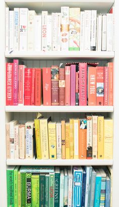 a book shelf filled with lots of books on top of white shelves next to each other