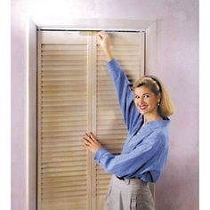 a woman standing in front of a window with blinds on the side and one arm up