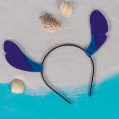 a blue and purple headband with seashells on the beach next to it