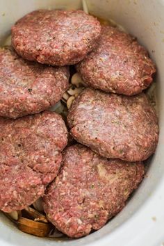 several hamburger patties in a white crock pot