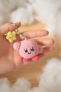 a hand holding a tiny stuffed animal keychain