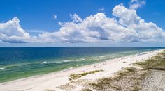 an aerial view of the beach and ocean with clouds in the sky over it,