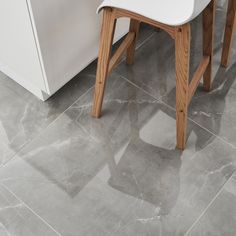 a white chair sitting on top of a gray tile floor next to a countertop