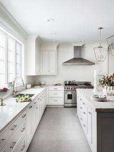 a large kitchen with white cabinets and stainless steel appliances, along with marble counter tops