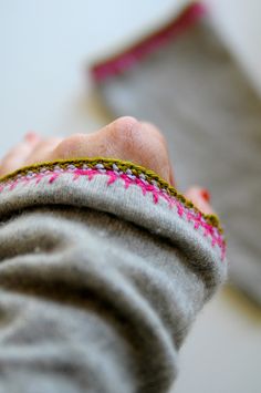 a person's hand is holding something that looks like a piece of cloth with pink thread on it