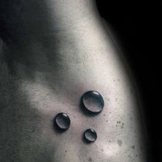 a man's stomach with three water drops on it