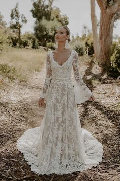 a woman standing in the woods wearing a wedding dress