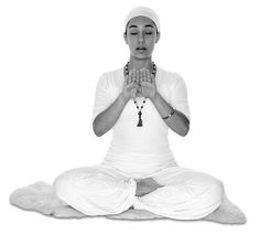 a woman sitting in a lotus position with her hands clasped up to her chest and eyes closed