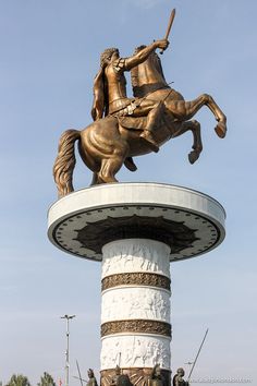 a statue of a man on a horse is in front of a white pillar and blue sky