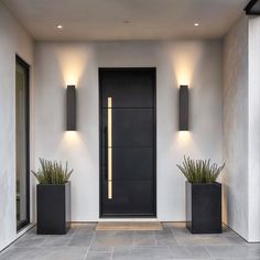 two black planters on the side of a white wall next to an entrance door