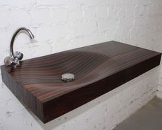 a wooden sink with chrome faucet and soap dispenser on it