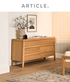 a wooden dresser sitting on top of a hard wood floor next to a white wall