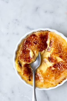 a bowl filled with food and a spoon on top of a marble countertop next to it