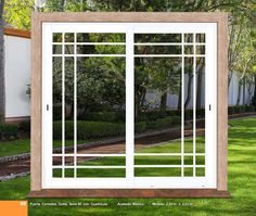 an open sliding glass door in front of a white house with trees and bushes behind it