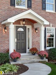 a front door with two planters on the steps and flowers in flower pots at the base