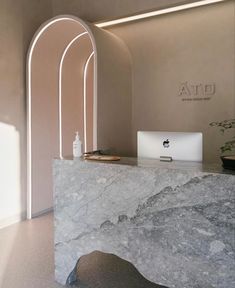 a marble counter top sitting in front of a white wall with arched windows and a laptop on it