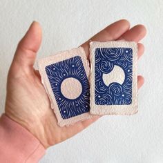 two small pieces of blue and white paper with circles on them are held in the palm of a person's hand