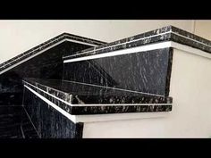 black marble steps with white trim and silver accents on the top, in front of a wall