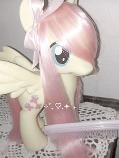 a little pony with pink hair sitting on top of a table