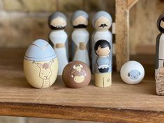 a group of wooden dolls sitting next to each other on top of a table in front of an egg