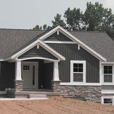 a gray house sitting on top of a dirt field