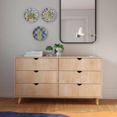 a wooden dresser sitting next to a mirror on top of a wall