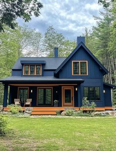 a blue house in the woods with lots of windows