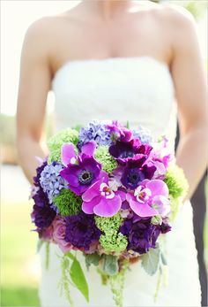 a bride holding a bouquet of purple and green flowers