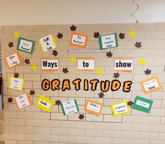 a bulletin board with the words, ways to show gratitude and leaves on it in front of a white brick wall